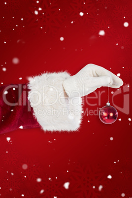 Composite image of santas hand is holding a christmas bulb