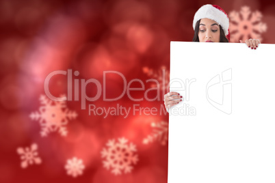 Composite image of beauty brunette in santa hat showing white po