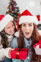 Composite image of festive mother and daughter exchanging gifts