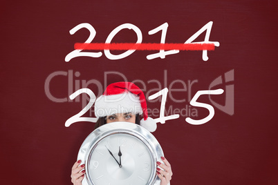 Composite image of festive brunette holding a clock