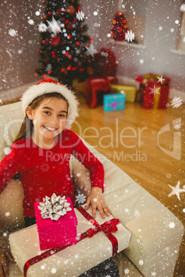 Composite image of festive little girl smiling at camera with gifts