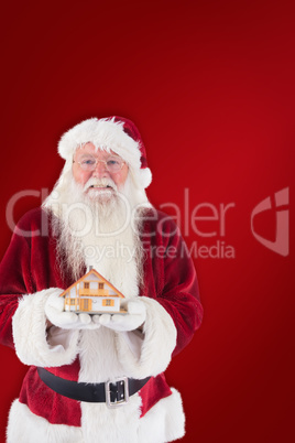 Composite image of santa holds a tiny house in his hands