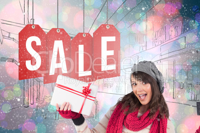 Composite image of brunette in winter clothes holding gift