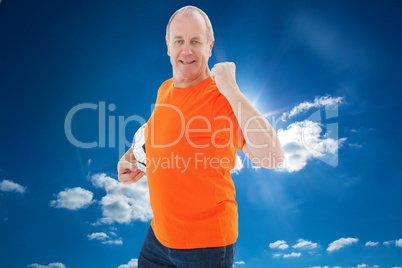 Composite image of mature man in orange tshirt cheering holding