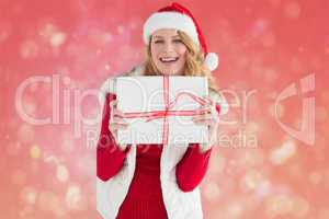 Composite image of pretty blonde in warm clothing holding a gift