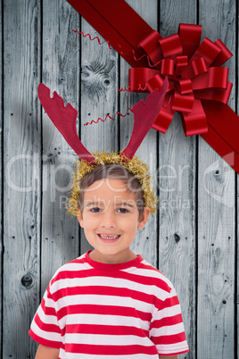 Composite image of cute little boy wearing antlers