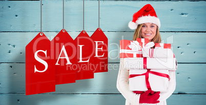 Composite image of festive blonde holding pile of gifts