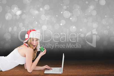 Composite image of happy woman shopping online lying on the floo