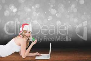 Composite image of happy woman shopping online lying on the floo