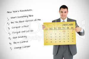 Composite image of businessman pointing at calendar he is holdin