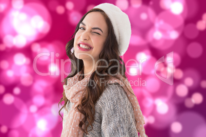 Composite image of brunette in winter clothes winking her eye