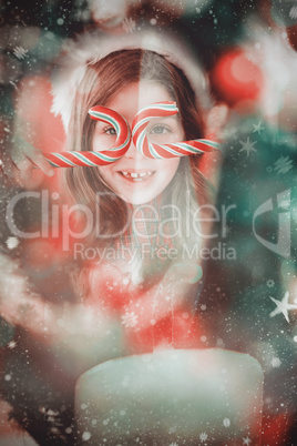 Composite image of happy little girl in santa hat holding candy