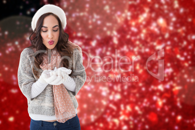 Composite image of pretty brunette in winter clothes blowing