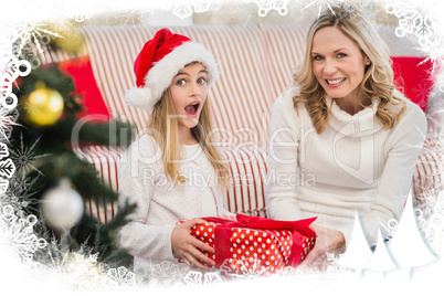 Composite image of festive mother and daughter on the couch with