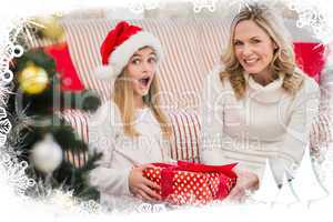 Composite image of festive mother and daughter on the couch with