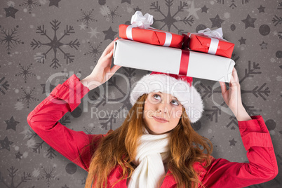 Composite image of festive redhead holding pile of gifts