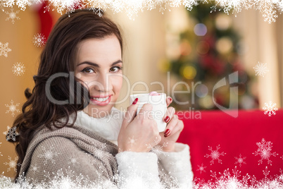 Composite image of smiling brunette holding a mug of hot chocola