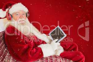 Composite image of father christmas listening to music with tabl