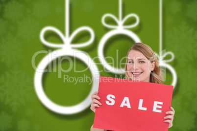 Composite image of cute blonde showing a red sale poster