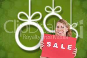Composite image of cute blonde showing a red sale poster