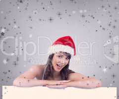 Composite image of festive brunette leaning on large poster