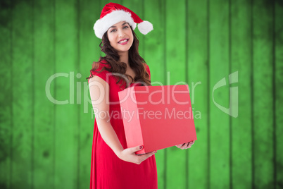 Composite image of festive brunette holding red box