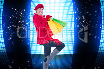 Composite image of happy blonde in winter clothes holding shoppi