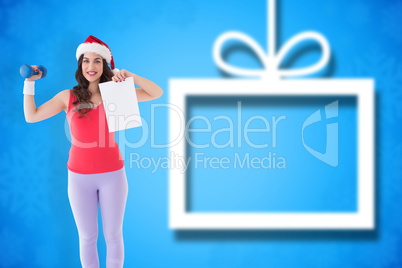 Composite image of festive athletic brunette holding page and du