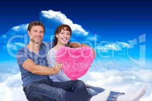 Composite image of couple holding a large heart