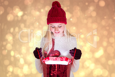 Composite image of festive blonde opening a gift bag