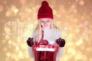 Composite image of festive blonde opening a gift bag