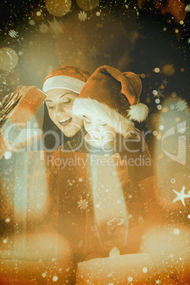 Composite image of festive mother and daughter opening a christm