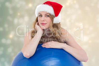 Composite image of festive fit blonde leaning on exercise ball