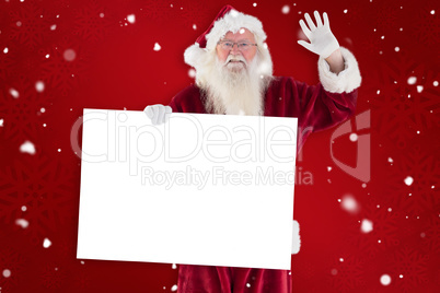 Composite image of santa holds a sign and is waving