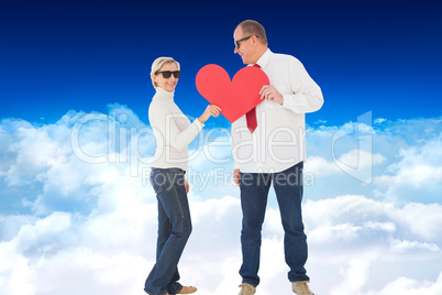 Composite image of older affectionate couple holding red heart s
