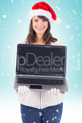 Smiling brunette in santa hat showing her laptop