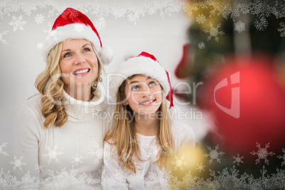 Composite image of festive mother and daughter smiling at tree