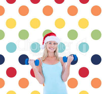 Composite image of festive fit blonde holding dumbbells