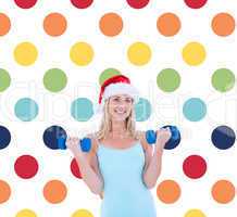 Composite image of festive fit blonde holding dumbbells