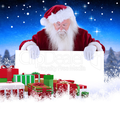 Composite image of santa holds a sign and looks down