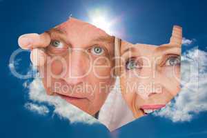 Composite image of older couple looking through rip