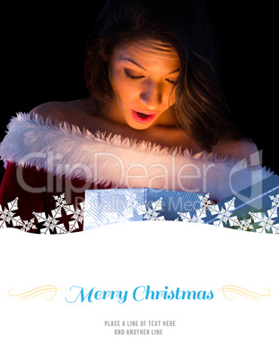 Composite image of pretty brunette in santa outfit opening gift