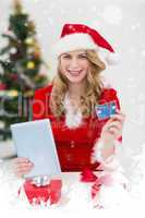 Composite image of festive blonde shopping online with tablet