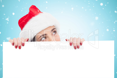 Composite image of pretty brunette in santa hat showing white po