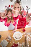 Composite image of festive mother and daughter making christmas cookies