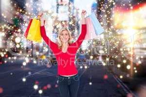 Composite image of happy blonde holding shopping bags