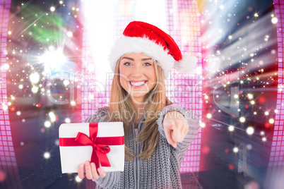 Composite image of festive blonde holding christmas gift