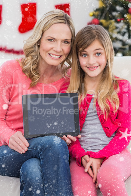 Composite image of festive mother and daughter showing tablet screen