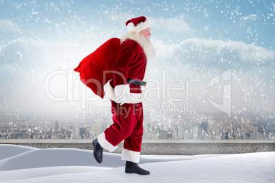 Composite image of santa standing on snowy ledge
