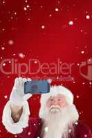 Composite image of santa taking a selfie on phone